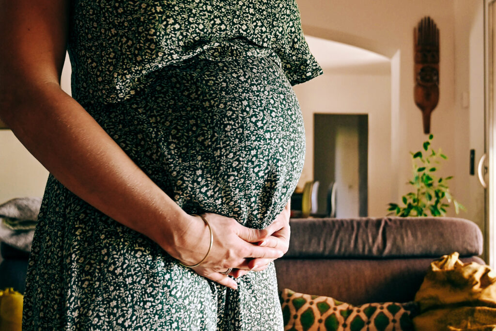 Ventre de femme enceinte en robe d'été verte par Simone Photographie