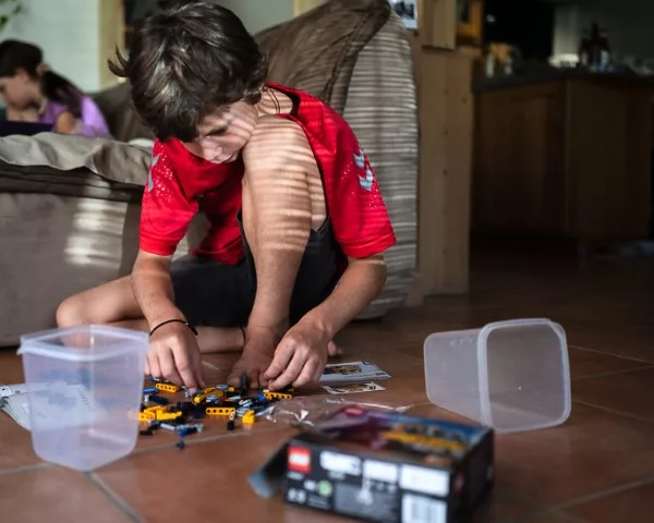 Enfant qui joue au sol avec ses légos dans la lumière