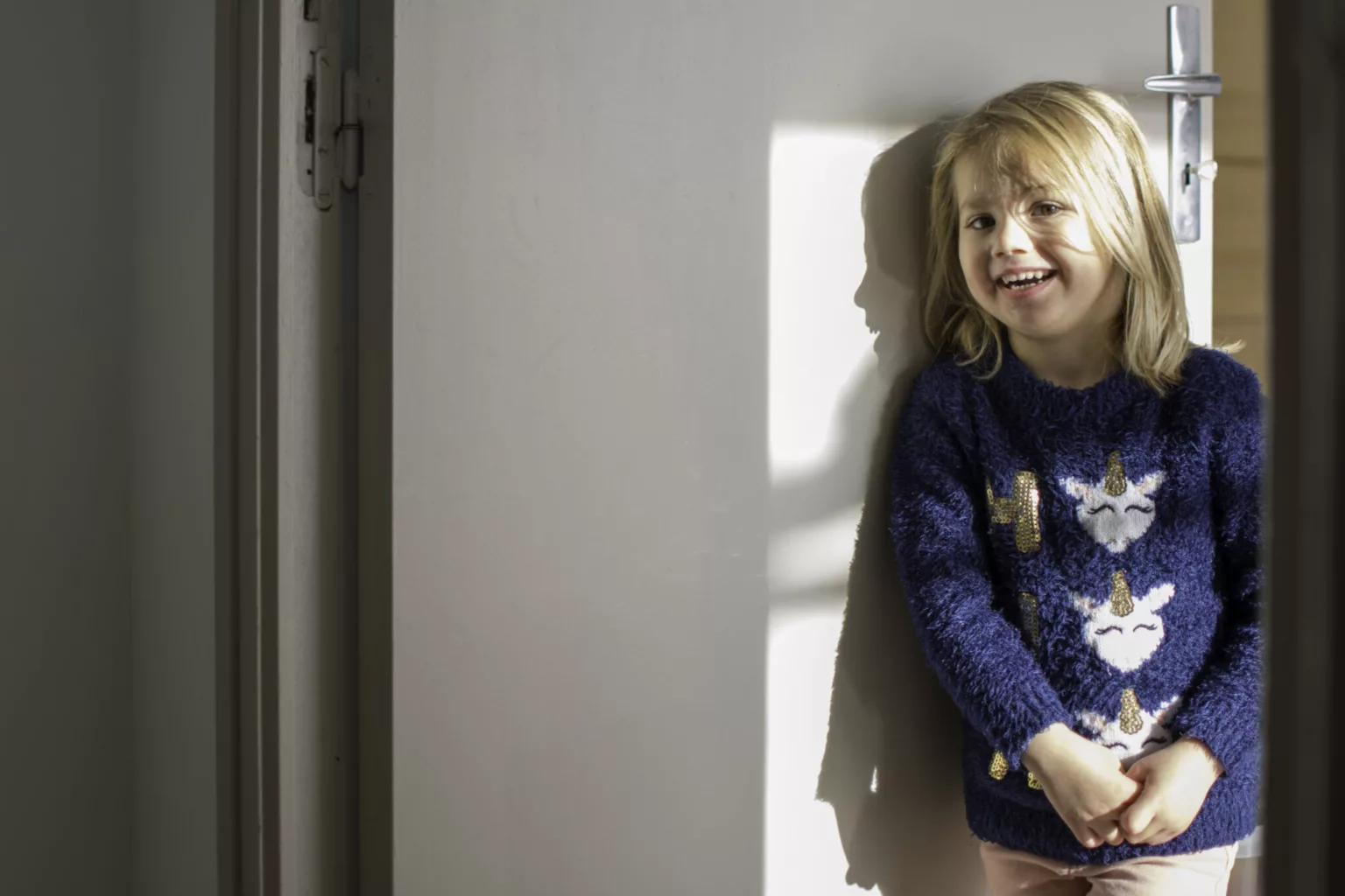 photo d'une petite fille souriante en pull bleu avec des licornes par Simone Photographie