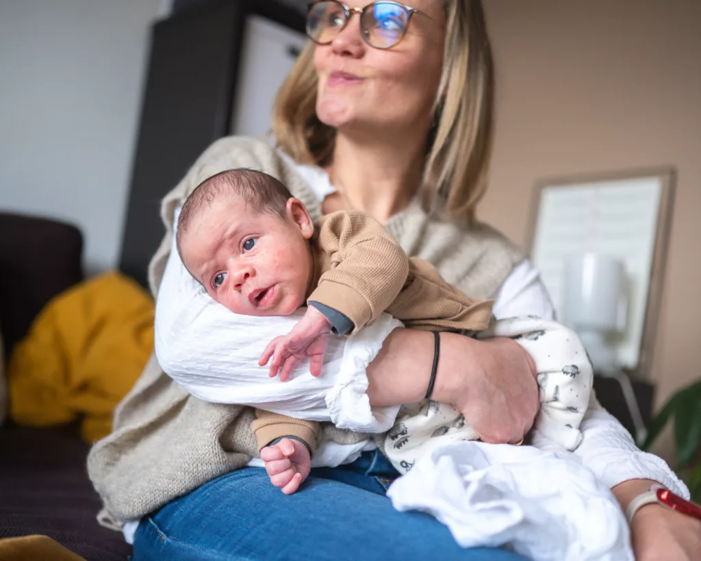 photo d'un bébé posé à plat ventre sur le bras de sa maman