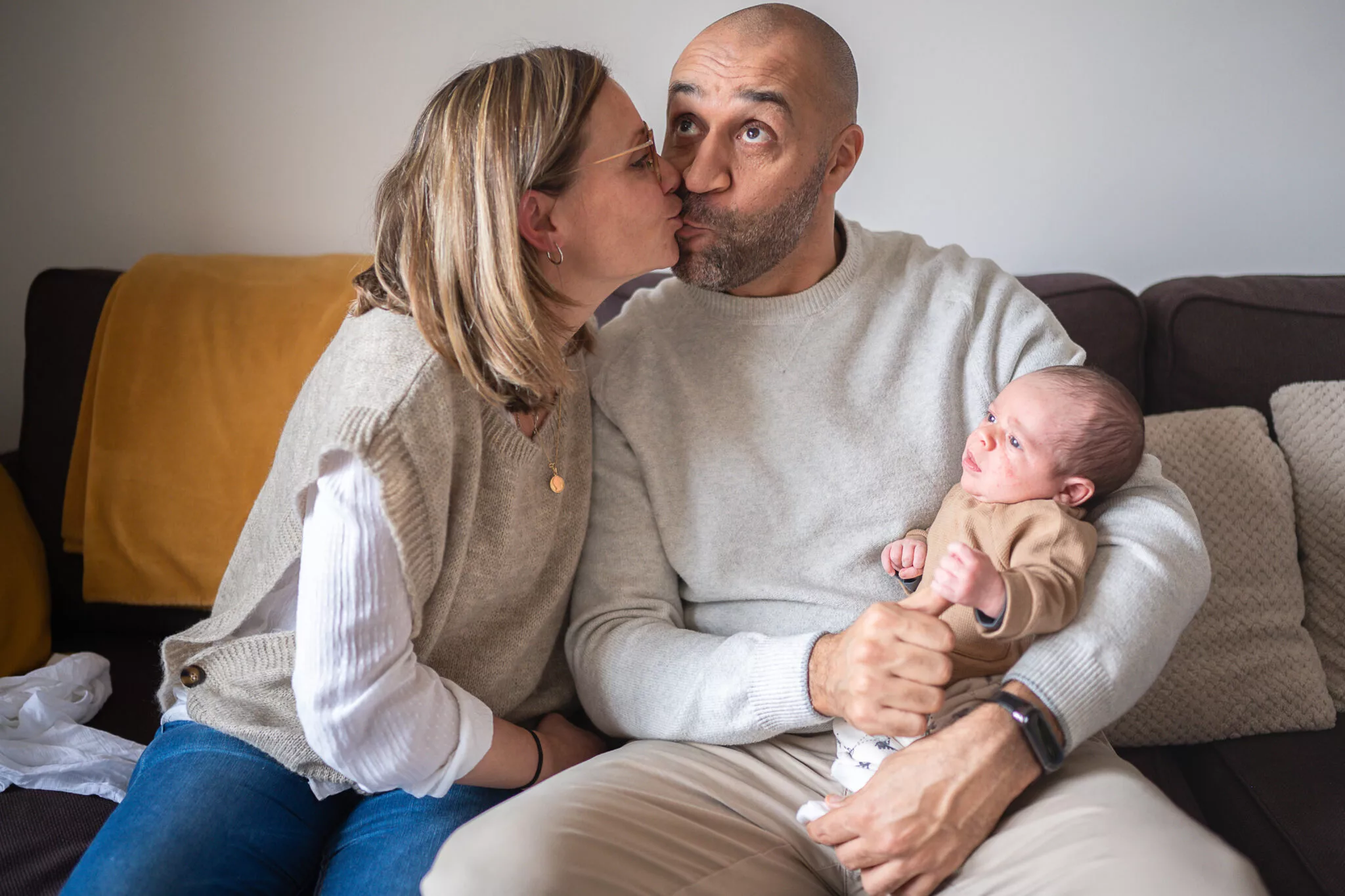 Photo d'un couple s'embrassant et de leur nouveau-né par simone photographe famille à grenoble