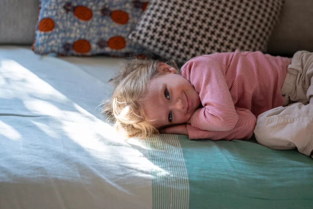 Enfant souriant allongé sur le côté sur un canapé