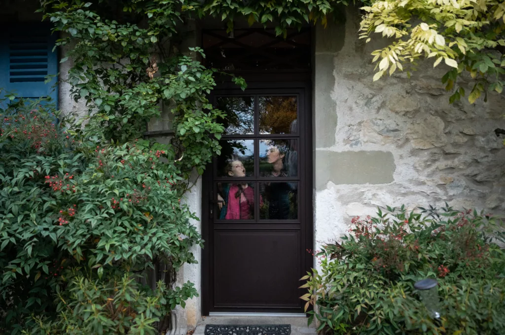 Mère et fille, la joue collée à la fenêtre, avec reflet du ciel