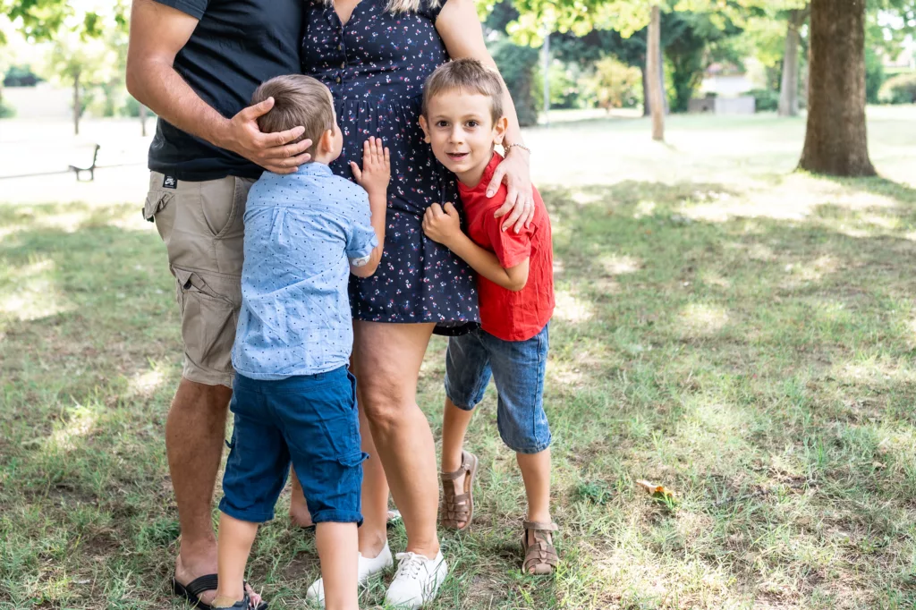 famille qui s'enlance et petit garcon qui embrasse le ventre rond de sa maman